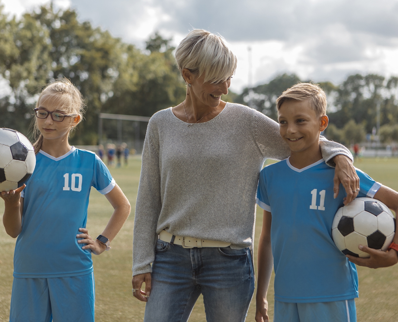 A mom with her two kids in soccer uniforms.